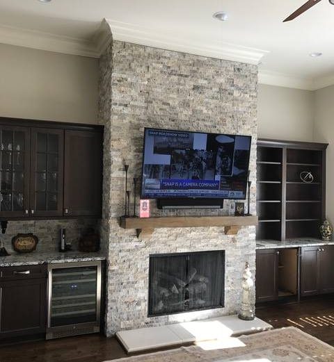 Tv mounted on mantle of stone fireplace